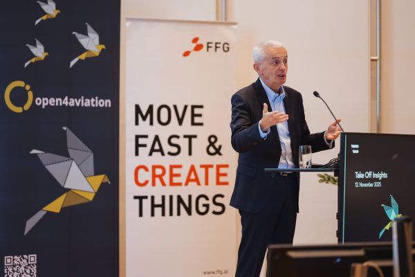 Mann mit weißen Haaren spricht ins Microphon beim Rednerpult.