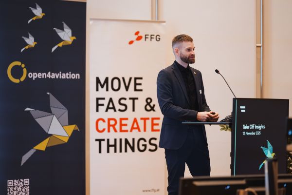 Ein Mann mit Bart Sakko und schwarzem Hemd spricht am Rednerpult.