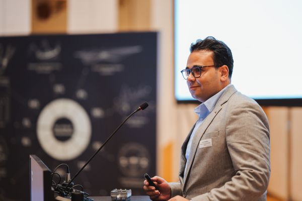 Ein Mann mit dunklen Haaren und hellem Anzug spricht am Rednerpult.