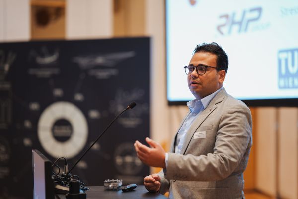 Ein Mann mit dunklen Haaren und hellem Anzug spricht am Rednerpult.