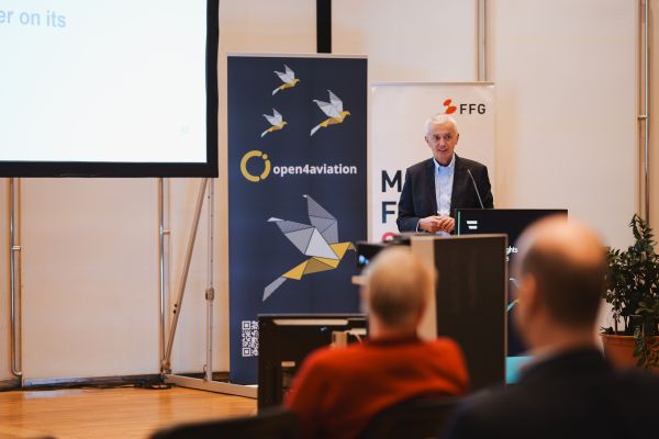 Mann mit weißen Haaren spricht ins Microphon beim Rednerpult.