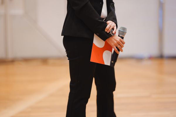 Eine Person haltet ein Microphon und einen Folder.