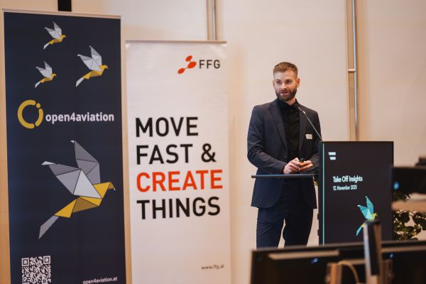 Ein Mann mit Bart Sakko und schwarzem Hemd spricht am Rednerpult.