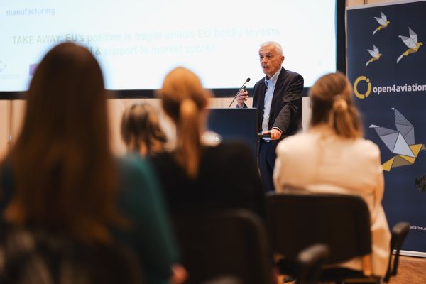 Mann mit weißen Haaren spricht ins Microphon beim Rednerpult.