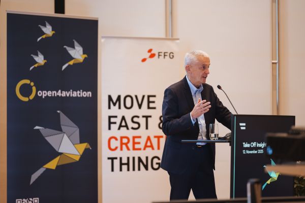 Mann mit weißen Haaren spricht ins Microphon beim Rednerpult.