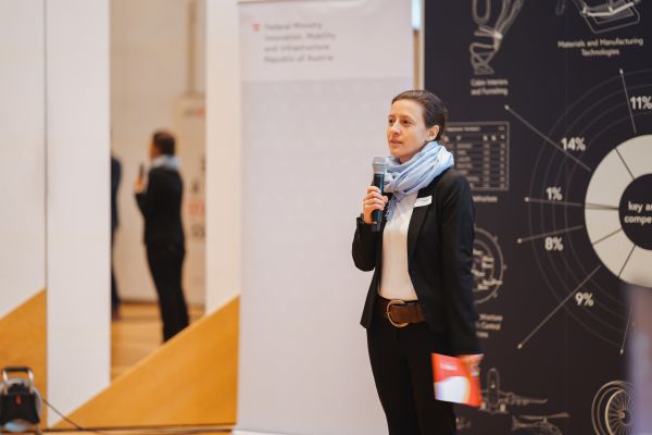 Eine Frau mit blauem Schal spricht ins Microphon