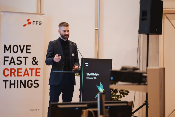 Ein Mann mit Bart Sakko und schwarzem Hemd spricht am Rednerpult.