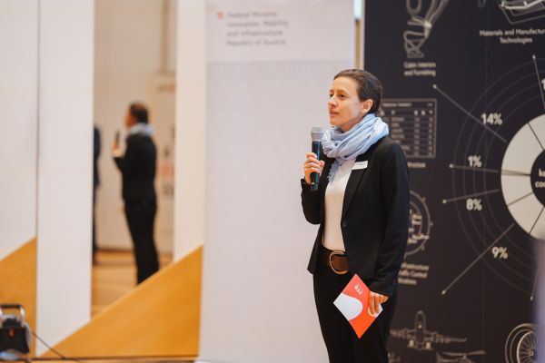 Eine Frau mit blauem Schal spricht ins Microphon