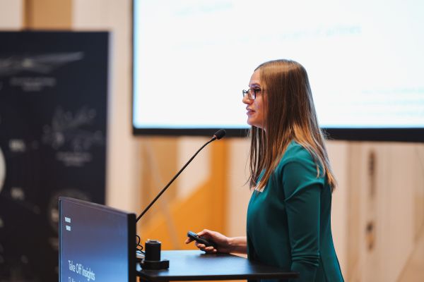 Eine Frau mit langen braunen Haaren redet am Rednerpult.