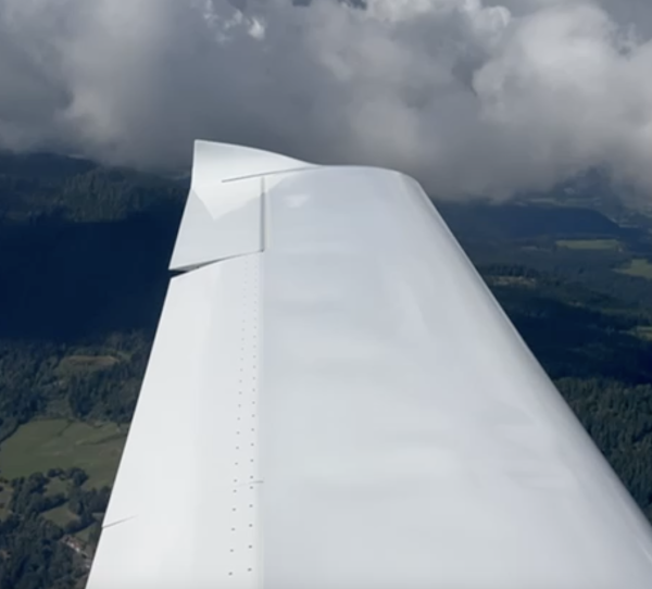 Flugzeugflügel in den Wolken weiter unten sieht man Wälder